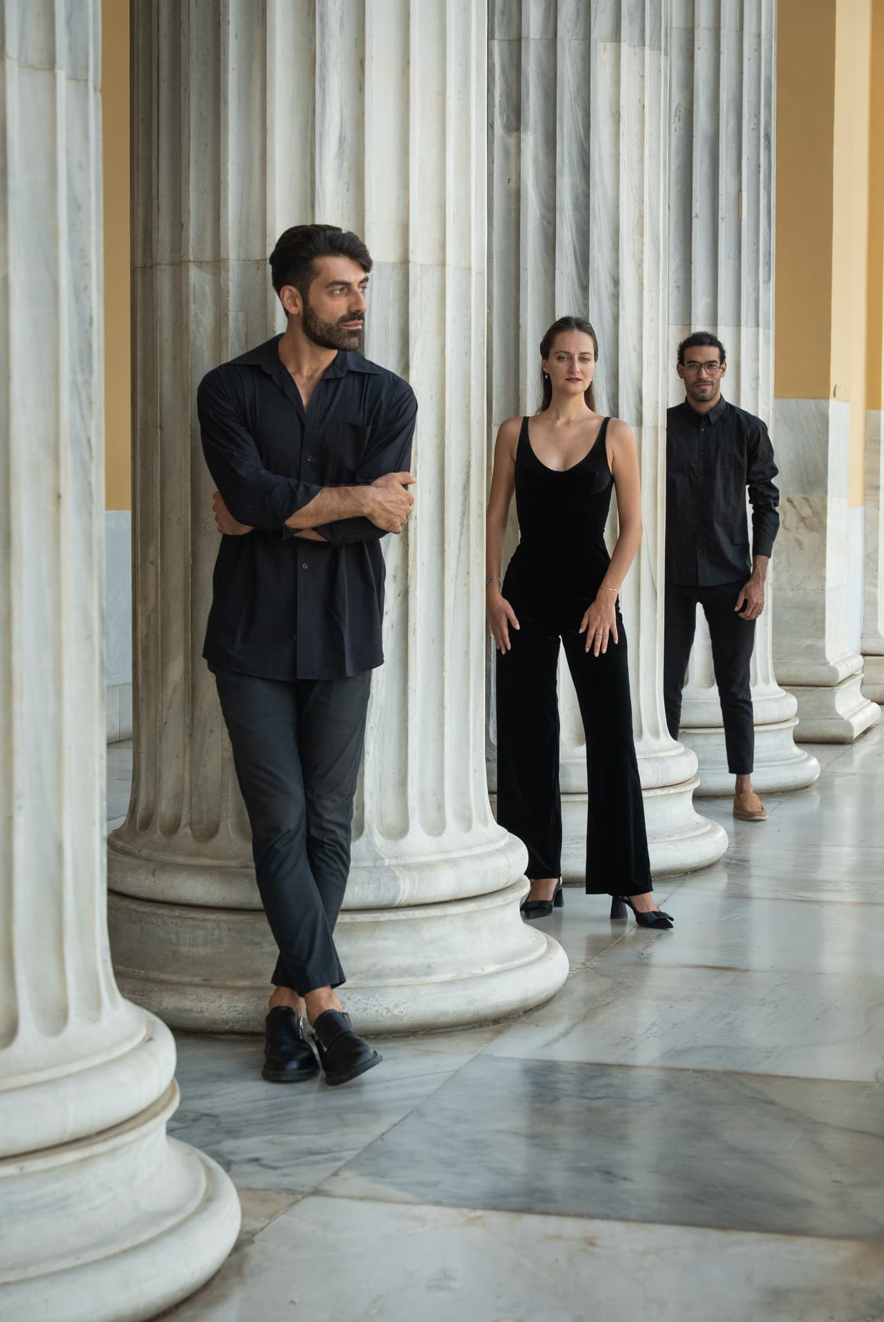 The trio in black between marble columns