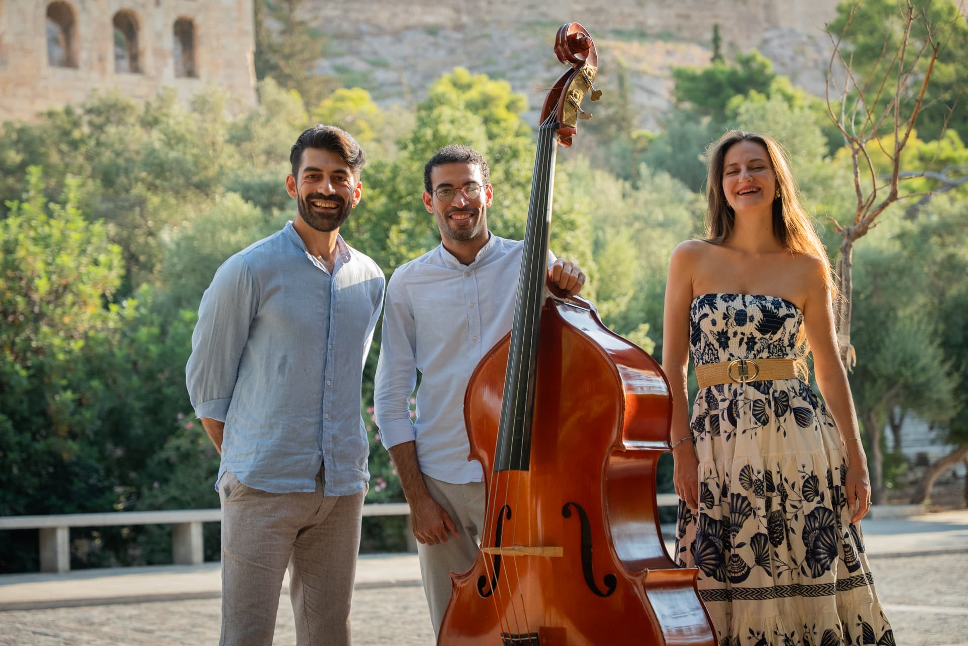 The Palintonos Trio with double bass in front of an ancient stone wall